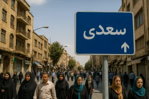 تابلوی آبیرنگی با نوشته «سعدی» در مرکز تصویر دیده میشود که در خیابانی شلوغ با ساختمانهای قدیمی و رهگذران متعدد قرار دارد؛ صحنهای واقعی از محله سعدی در یک روز آفتابی.