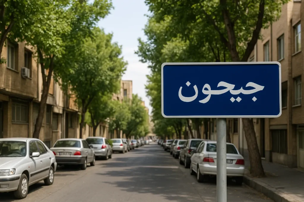 نمایی از خیابان آرام و درخت‌کاری‌شده در محله جیحون، با ساختمان‌های آجری در دو طرف، خودروهای پارک‌شده در حاشیه خیابان و تابلوی آبی‌رنگی که نام «جیحون» روی آن نوشته شده است.