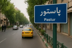 تابلوی آبیرنگ خیابان پاستور تهران در کنار خیابانی آرام و درختکاریشده دیده میشود؛ چند خودرو از جمله یک تاکسی زرد در حال حرکتاند و عابران در پیادهرو قدم میزنند.