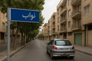 تابلوی آبی‌رنگی با نوشتهٔ «نواب» در ابتدای خیابانی آرام و درخت‌کاری‌شده دیده می‌شود؛ در دو طرف خیابان ساختمان‌های آجری چندطبقه قرار دارند و یک خودروی نقره‌ای در کنار خیابان پارک شده است.