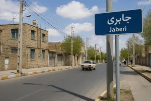تابلوی آبیرنگ خیابان جابری در کنار خیابانی آرام با خانههای خشتی و درختان سبز در یک روز آفتابی.