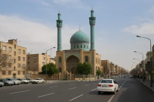نمایی از خیابان اصلی محله تهران نو در تهران که مسجدی با گنبد و مناره‌های فیروزه‌ای در مرکز تصویر دیده می‌شود و ساختمان‌های مسکونی و خودروها در دو طرف خیابان قرار دارند.