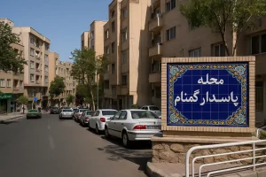 نمایی از محله پاسدار گمنام در تهران؛ خیابانی آرام با ساختمان‌های آجری چندطبقه، خودروهای پارک‌شده در حاشیه و تابلوی سرامیکی آبی‌رنگی که نام محله را نشان می‌دهد.